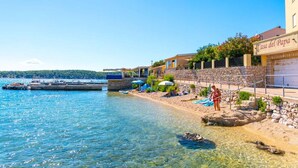 A coastal hotel with a stone facade, a beach area with umbrellas, and a clear view of the sea. - Apartment in Barbat with Balcony, Air condition (660-3) (Rab)