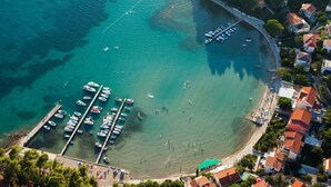 An aerial view of a coastal marina with boats docked, a sandy beach, and residential buildings with red roofs. - Apartment in Barbat with Balcony, Air condition (660-3) (Rab)