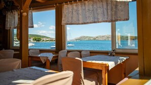 A restaurant with wooden furniture and large windows overlooking a coastal view. - Apartment in Barbat with Balcony, Air condition (660-3) (Rab)