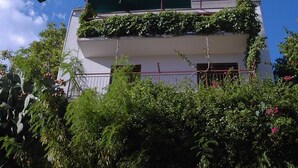 Ein zweistöckiges Gebäude mit einem mit Grünwerk bewachsenen Balkon.