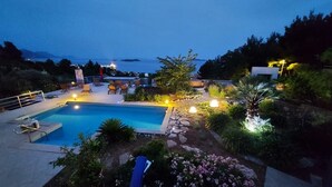 Una piscina circondata da sdraio con vista sul mare al crepuscolo.
