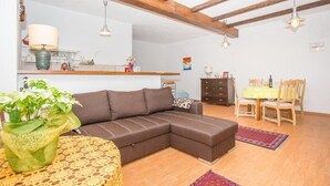 Un accogliente soggiorno con un divano componibile, un tavolo da pranzo con sedie e una zona cucina sullo sfondo.