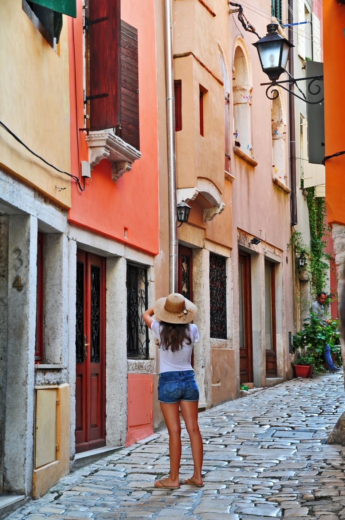 A narrow cobblestone street with buildings featuring traditional architecture and red doors.