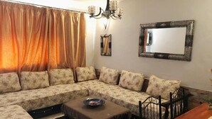 Ein Wohnzimmer mit einem Ecksofa, einem Couchtisch, einem Esstisch und einer Pendelleuchte.