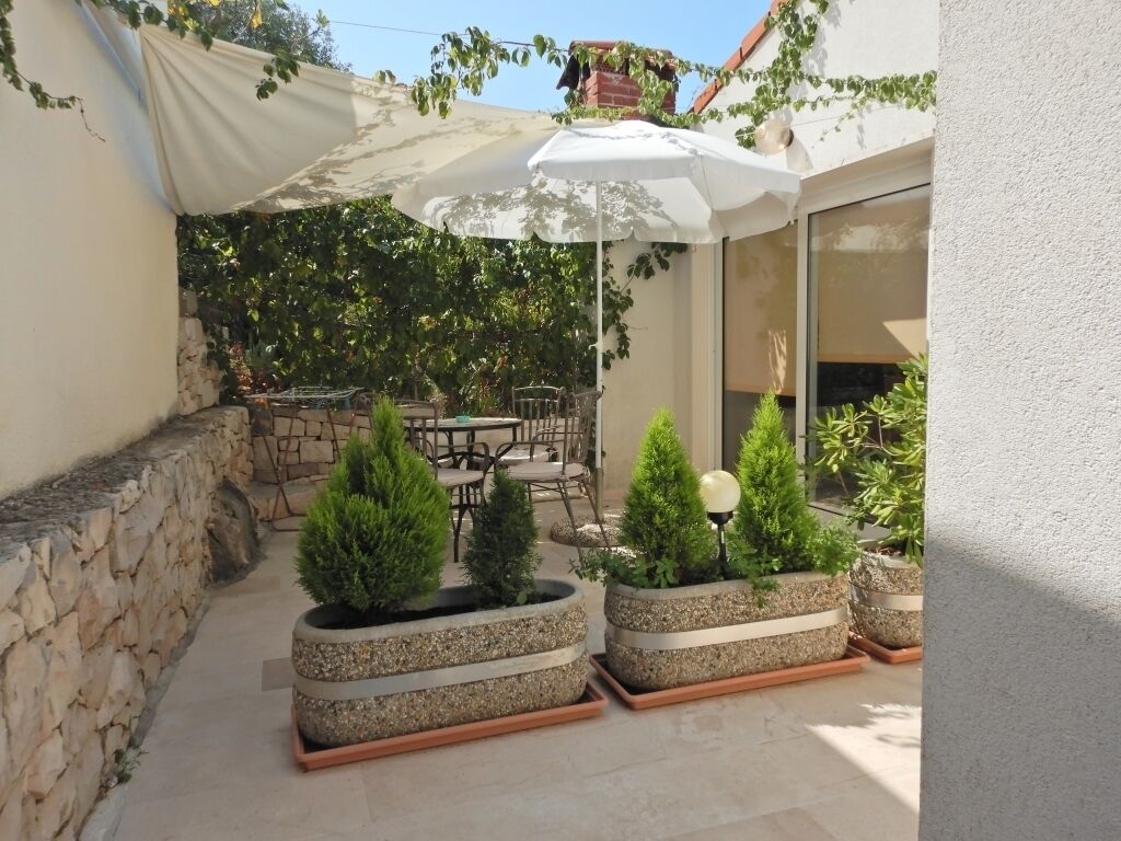 A patio area with stone planters, a white umbrella, and outdoor furniture.