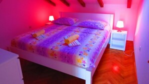 Une chambre à coucher avec un lit, deux tables de chevet et une lucarne.