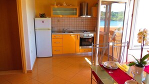 Une cuisine équipée d’un réfrigérateur, d’un four et d’un évier. On y trouve une table à manger avec des chaises, ainsi qu’une fenêtre donnant sur un paysage magnifique.