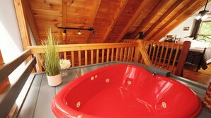 Un jacuzzi rojo en una habitación de madera con balcón.