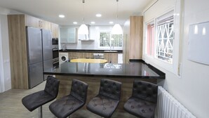 A modern kitchen with a central island, pendant lighting, and a view of the outdoors through a window. - Villa Romera Rural Cottage for 25 people (Cardedeu)