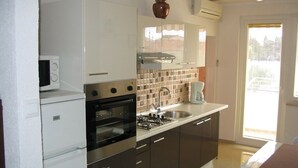Una cocina moderna con electrodomésticos de acero inoxidable, salpicadero de azulejos y un ventanal que proporciona luz natural.