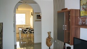 Un interior con comedor, un mueble de madera con televisor y un jarrón.