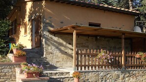 Ein rustikales Steinhaus mit einer Holzveranda und Treppen zum Eingang.