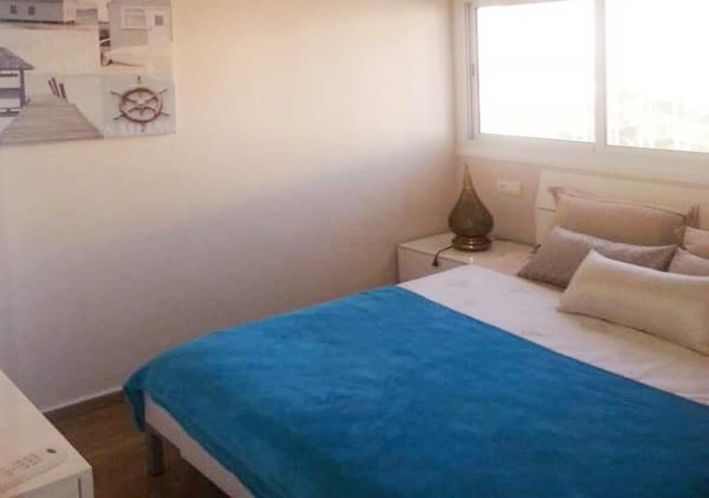 Une chambre à coucher avec un lit, une table de chevet, une lampe et un élément décoratif mural.