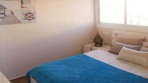 Een slaapkamer met een bed, nachtkastje, lamp en een decoratie aan de muur.