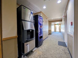 A hotel hallway with a vending machine, a refrigerator, and a carpeted floor. - Great Studio condo only steps from the Lifts! Hot Tubs and Fire Pit on site (Keystone)