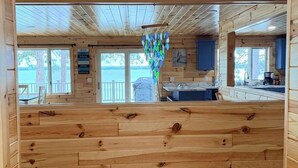 A wooden cabin interior with a kitchen area, wooden walls, and a view through the windows. - Veeder Lodge | West Twin Lake Retreat (Lewiston)