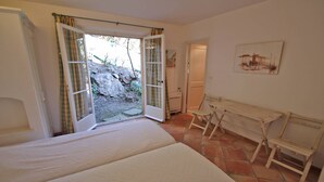 A bedroom with a bed, a desk, and an open door leading to a garden. - Villa 10 people – Private infinity pool – Sea view – Wifi – Air conditioning – Sainte... (STE MAXIME)