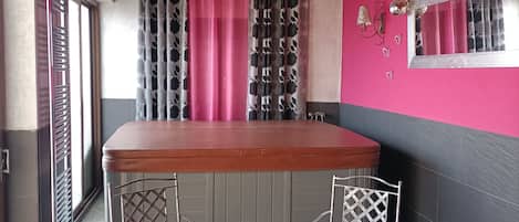 Una cocina con mostrador de madera, dos sillas de metal con cojines rosados y una mesa pequeña con una bandeja de objetos.