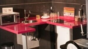 A compact kitchen with a red countertop, a microwave, a sink, and a stainless steel range hood. - Mudayyan house for couples or small families. (Coca de Alba)