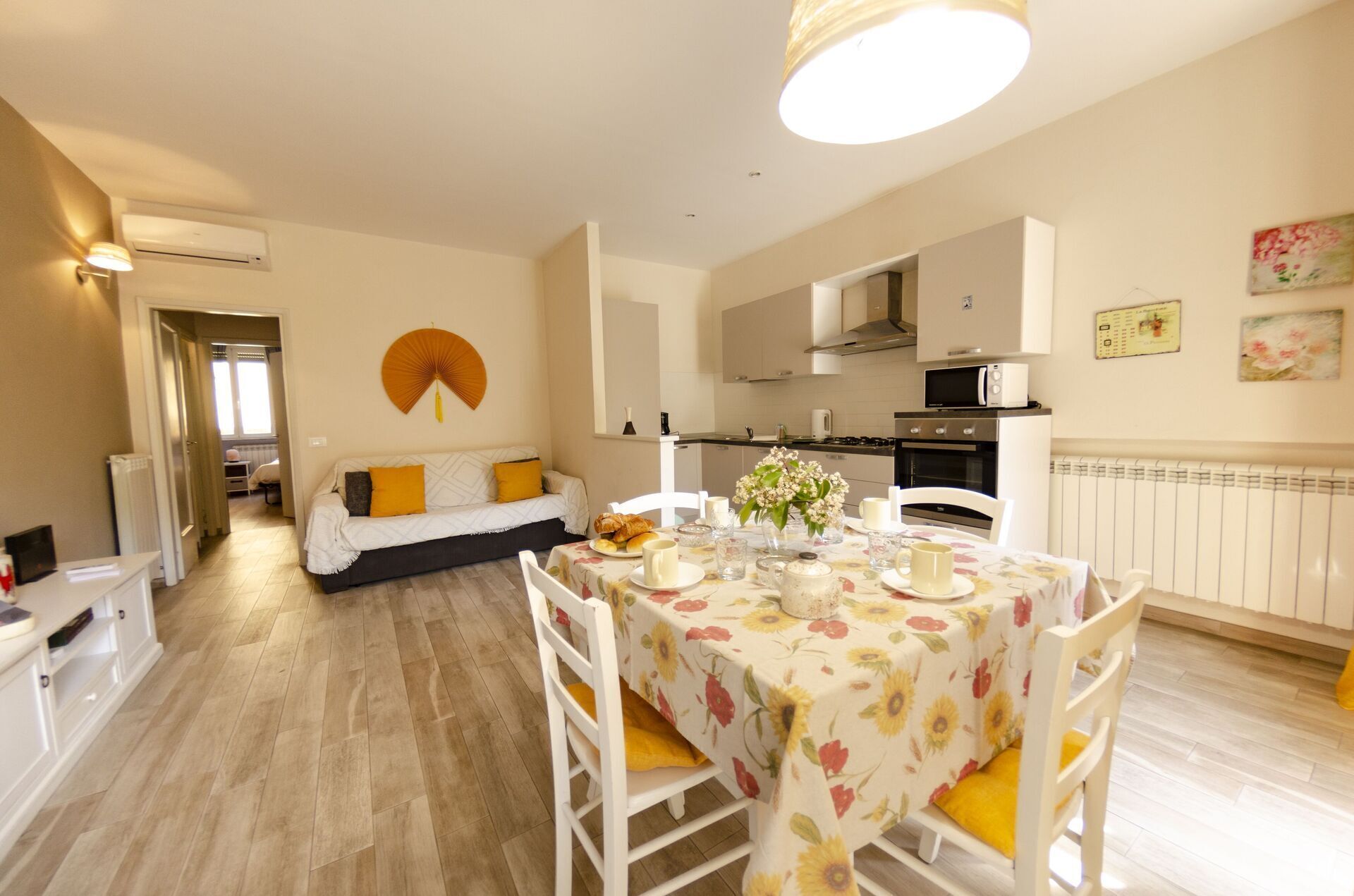 A cozy living room with a sofa, a dining table set for two, and a kitchen in the background.