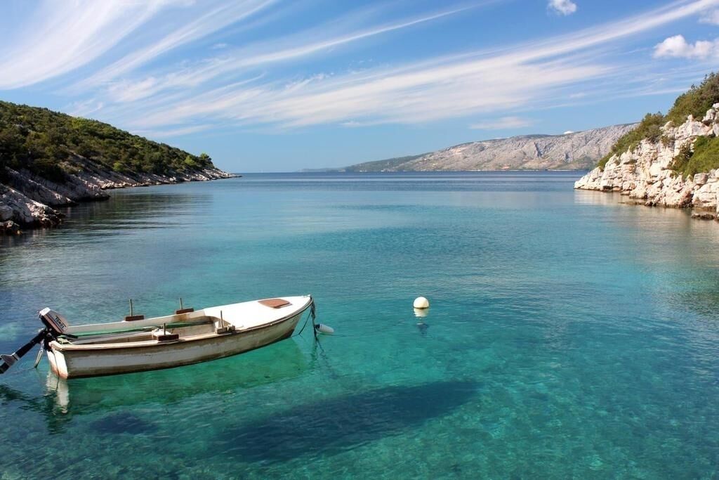 A boat anchored in clear turquoise water with rocky cliffs on both sides.
