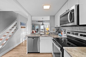Cocina moderna con electrodomésticos de acero inoxidable, lavavajillas y encimera de granito.