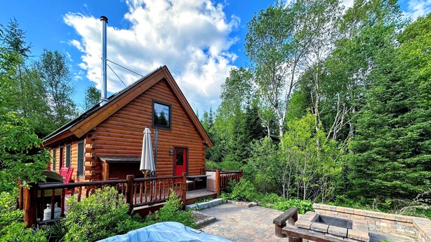 A wooden cabin with a hot tub and outdoor seating area surrounded by trees. - BC Log cabin 1 mile from Mt Washington Hotel, beach, slope views! Hot tub, volleyball, trails! (Bretton Woods)
