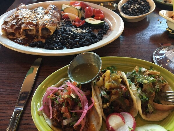 A dining table with plates of food, including tacos and a dish with beans and vegetables. - Platinum location, NO STEPS. Ground Floor End Unit at Marbeya in ParadiseValley (Scottsdale)