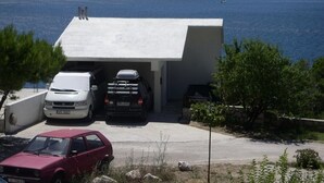 Een modern huis met een garage waarin twee auto's staan, en een rode auto geparkeerd voor het huis.