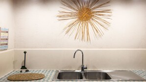 A kitchen with a double sink, a decorative sunburst wall art, and a small woven mat on the counter. - Country Resort in Torre Suda with 2 bedrooms sleeps 4 (Torre Suda)