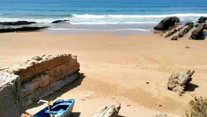 A beach with a boat, rocky formations, and the ocean. - Imi Ouaddar Estivage Center 4333 (Imi Ouaddar)