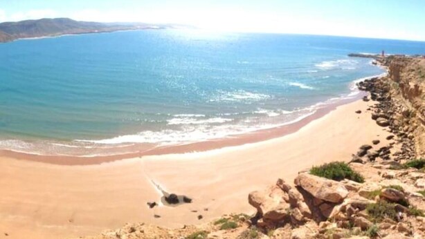 A beach with clear blue water, sandy shore, and rocky outcrops. - Imi Ouaddar Estivage Center 4333 (Imi Ouaddar)