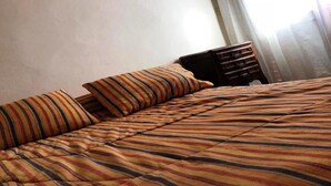 Un lit avec une literie à rayures et une table de chevet en bois dotée de tiroirs.