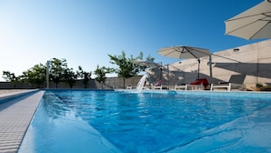 Una piscina con tobogán de agua, sillas de descanso y sombrillas.