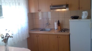 A compact kitchen with wooden cabinets, a sink, a stove, and a refrigerator.