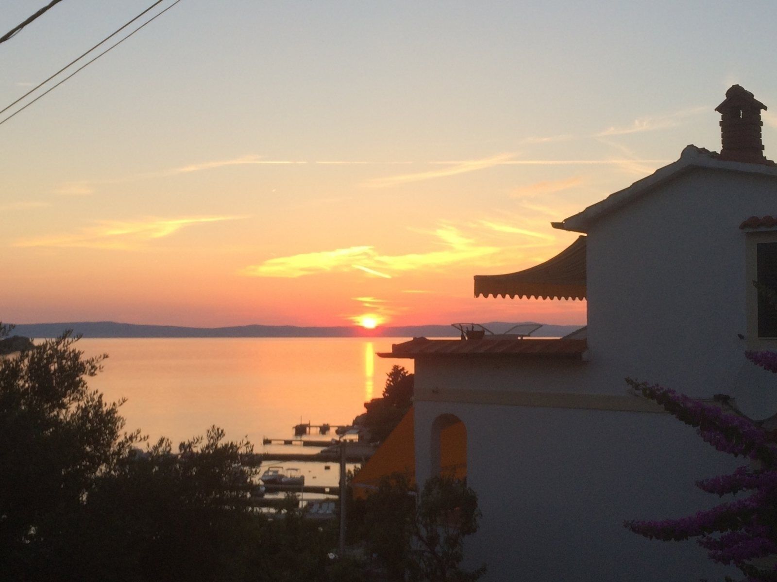 A building with a traditional architectural style, overlooking a calm body of water during sunset.