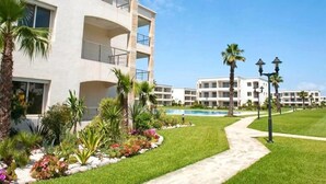 Ein mehrstöckiges Hotel mit Pool, umgeben von gepflegten Rasenflächen und Palmen.
