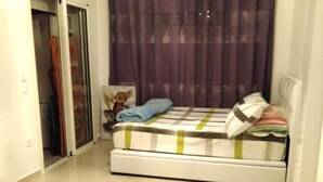 Ein Schlafzimmer mit einem Bett, einem Fenster mit Vorhängen, einer Tür und einem Wandbild.