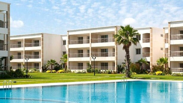 Ein modernes Hotel mit Schwimmbad, mehreren Balkonen und üppiger Bepflanzung.
