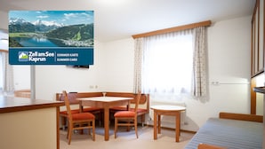 Una habitación con mesa de comedor, sillas, cama y televisor que muestra una vista panorámica.