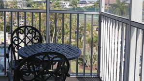 Un balcón con mesa y sillas, con vistas a una zona residencial con casas y palmeras.