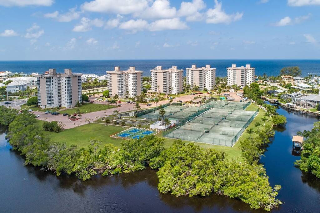 A coastal residential area with high-rise buildings, a tennis court, and a marina.