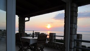 Patio con tavolo e sedie, vista su uno specchio d'acqua al tramonto.