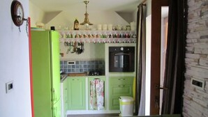 Una cucina con mobili verdi, un fornello e un cestino.