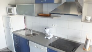 Een moderne keuken met blauwe kastjes, een magnetron, een koffiezetapparaat en een vaatwasser.