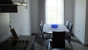 Een moderne keuken met een fornuis, spoelbak en een eethoek met een tafel en stoelen.