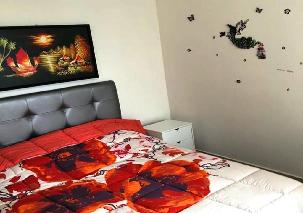 Ein Schlafzimmer mit einem Bett, einem grauen Kopfteil, einem gerahmten Bild an der Wand und Schmetterlingsstickern an der Wand.