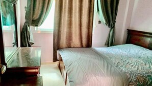 A bedroom with a bed, a nightstand, and curtains. - Nice apartment in residence Zina Sidi Bouzid 4306 (Sidi Bouzid)