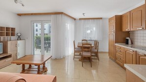 Une cuisine moderne avec des meubles en bois, une table à manger et une porte-fenêtre coulissante donnant sur un balcon.