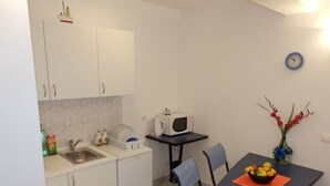 Une cuisine compacte avec des meubles blancs, un four à micro-ondes, un évier et une table à manger avec des chaises.
